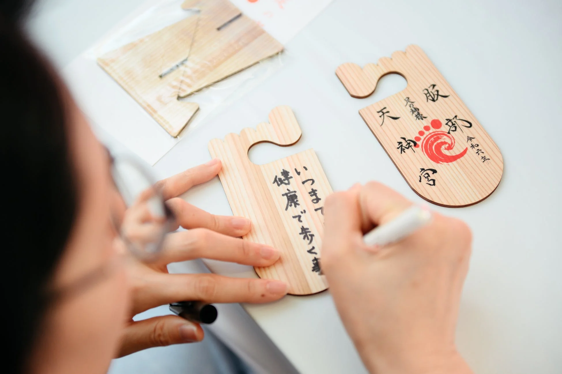 足の形をした絵馬に願い事を書く様子