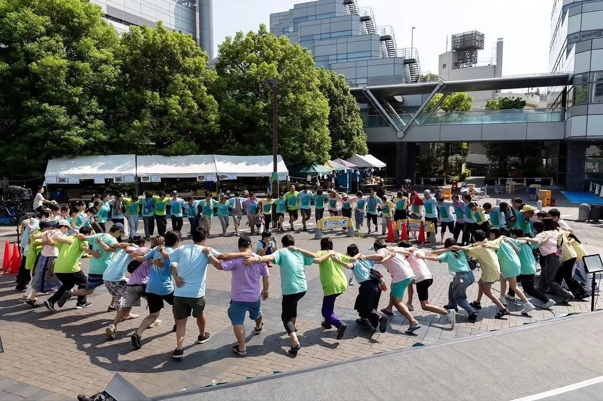 多くの人々が肩を組み輪になって踊る様子