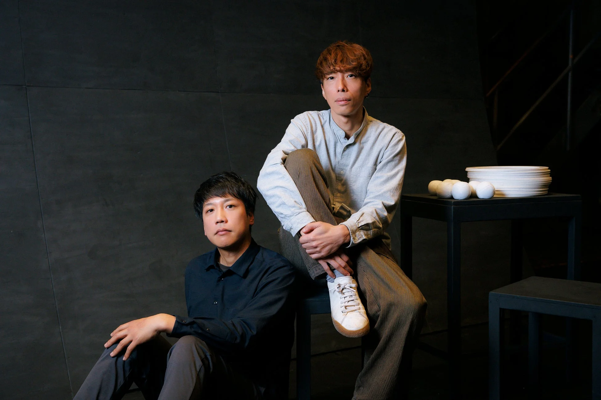 暗い背景でポーズをとる二人組のアジア人男性