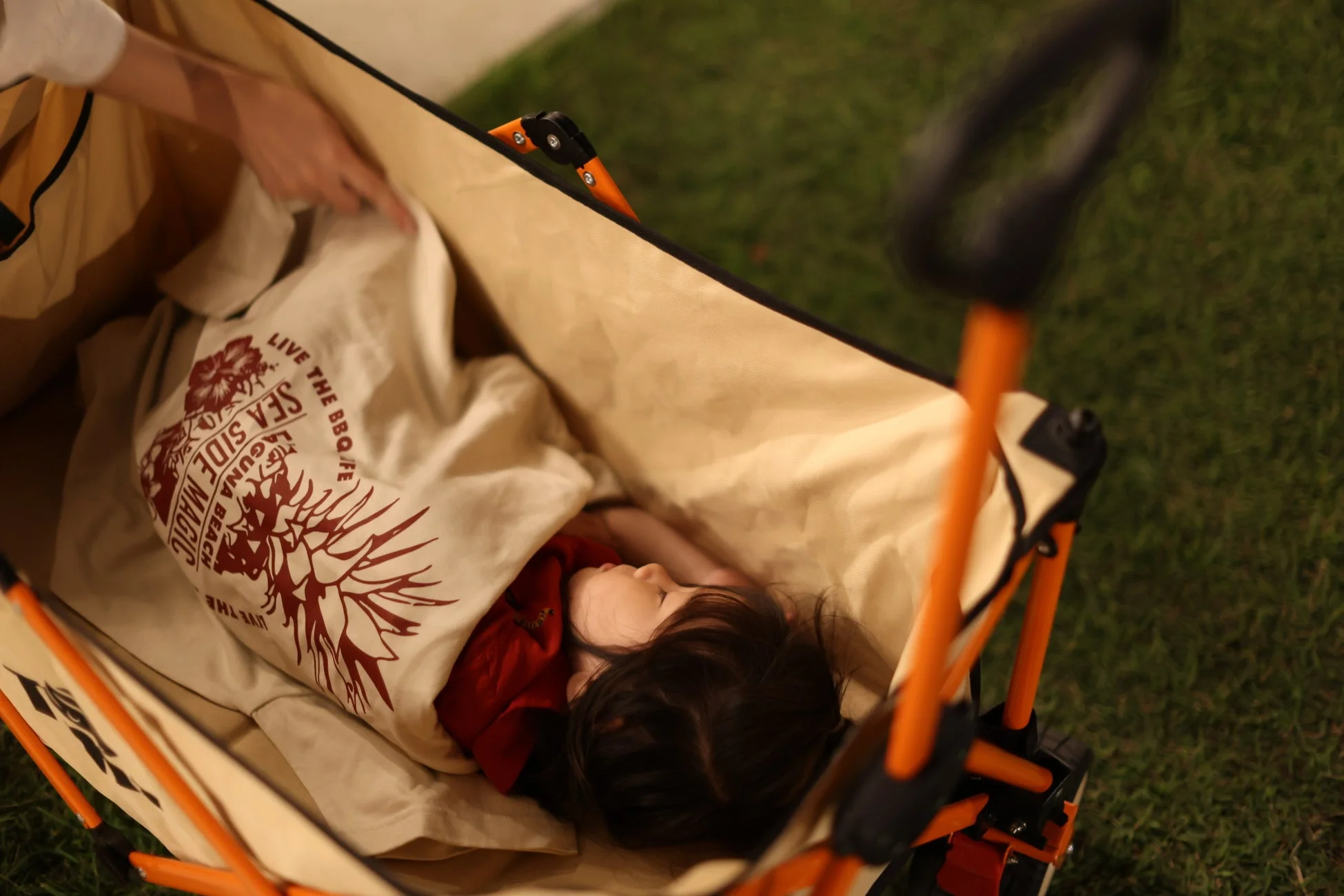 屋外のワゴンの中で眠る子供