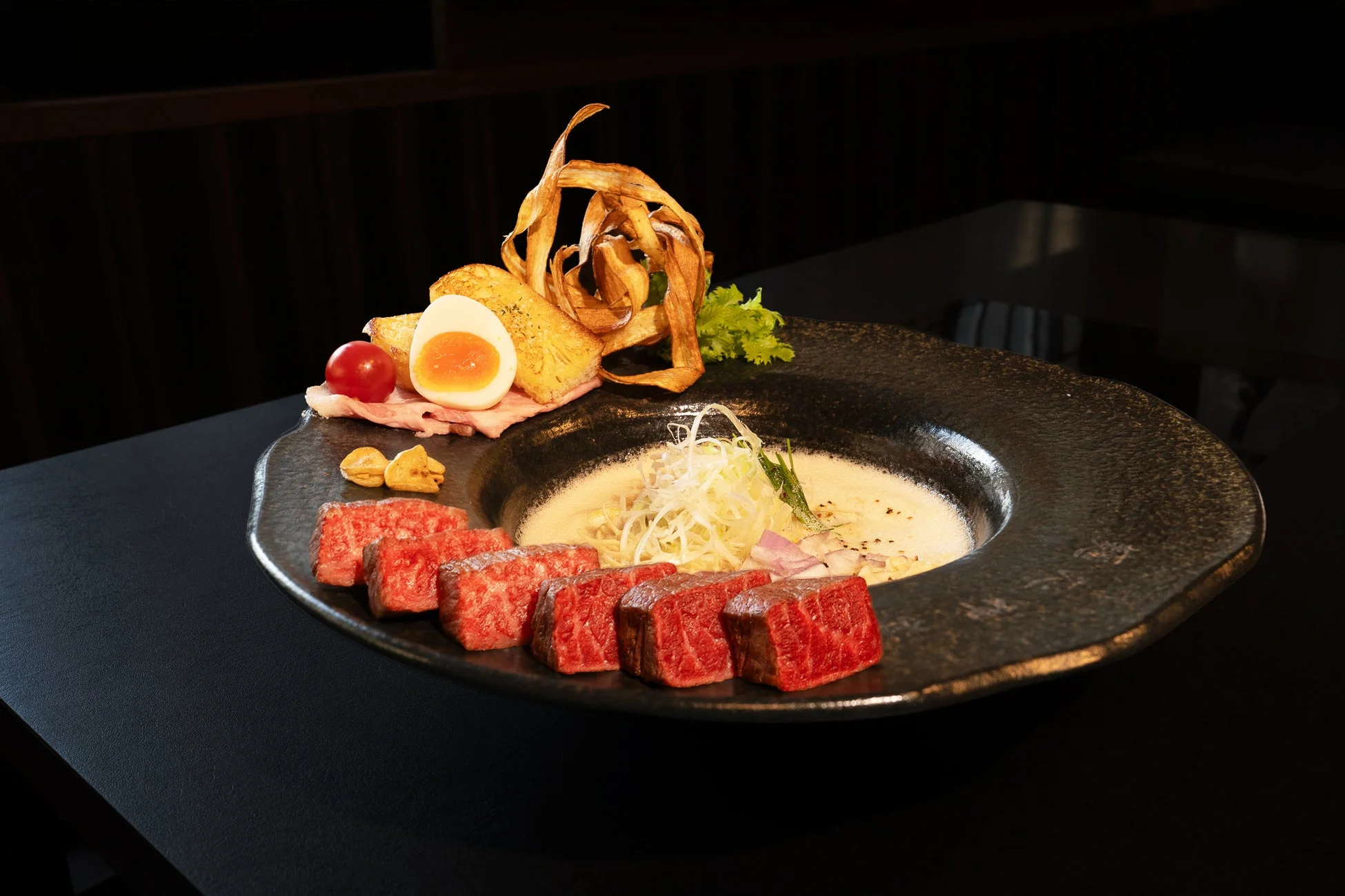 サイコロ状の和牛、半熟卵などが添えられた麺料理