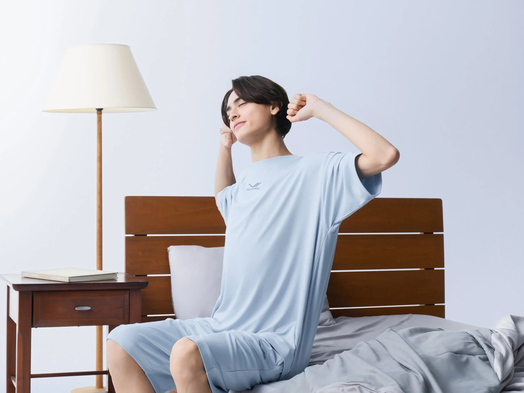 ベッドで伸びをする男性