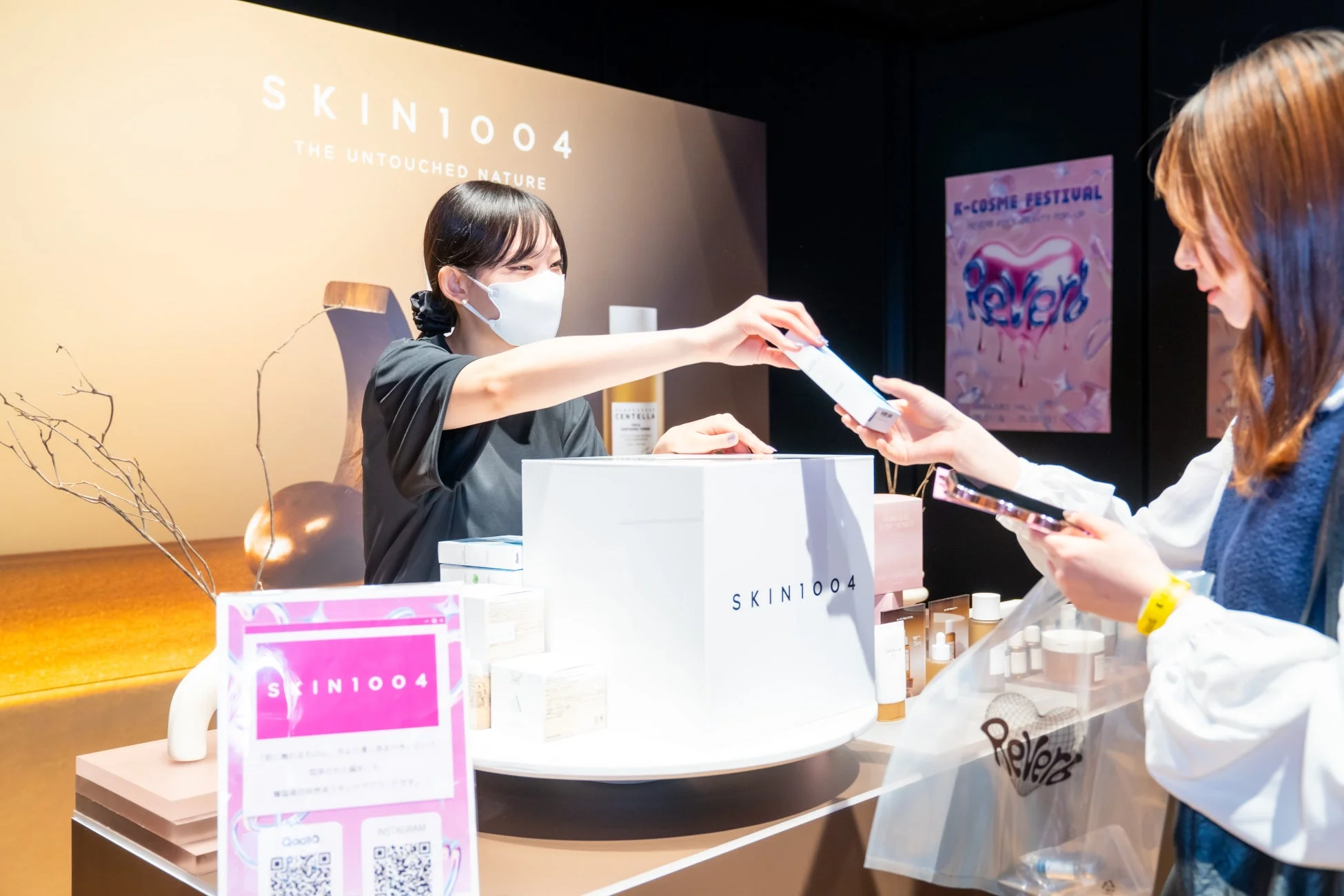 K-COSME FESTIVALの会場でスタッフが顧客にSKIN1004の製品を手渡している様子