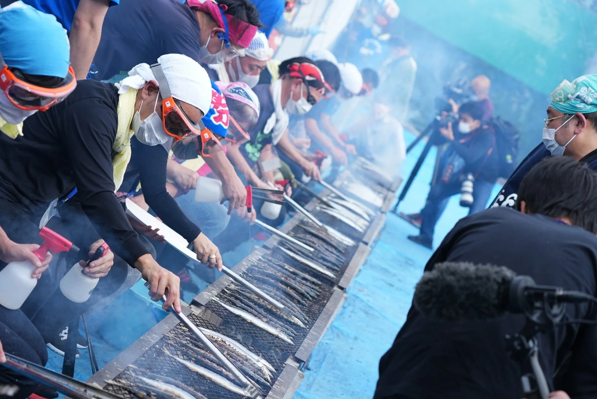 大勢の人が炭火で秋刀魚を焼く様子