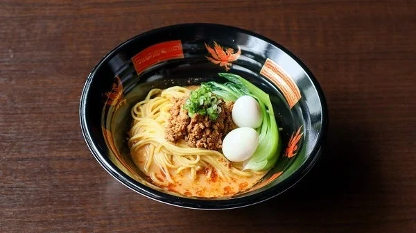 挽肉、青菜、うずらの卵がトッピングされた、濃厚なスープのラーメンが黒い器に入っています。
