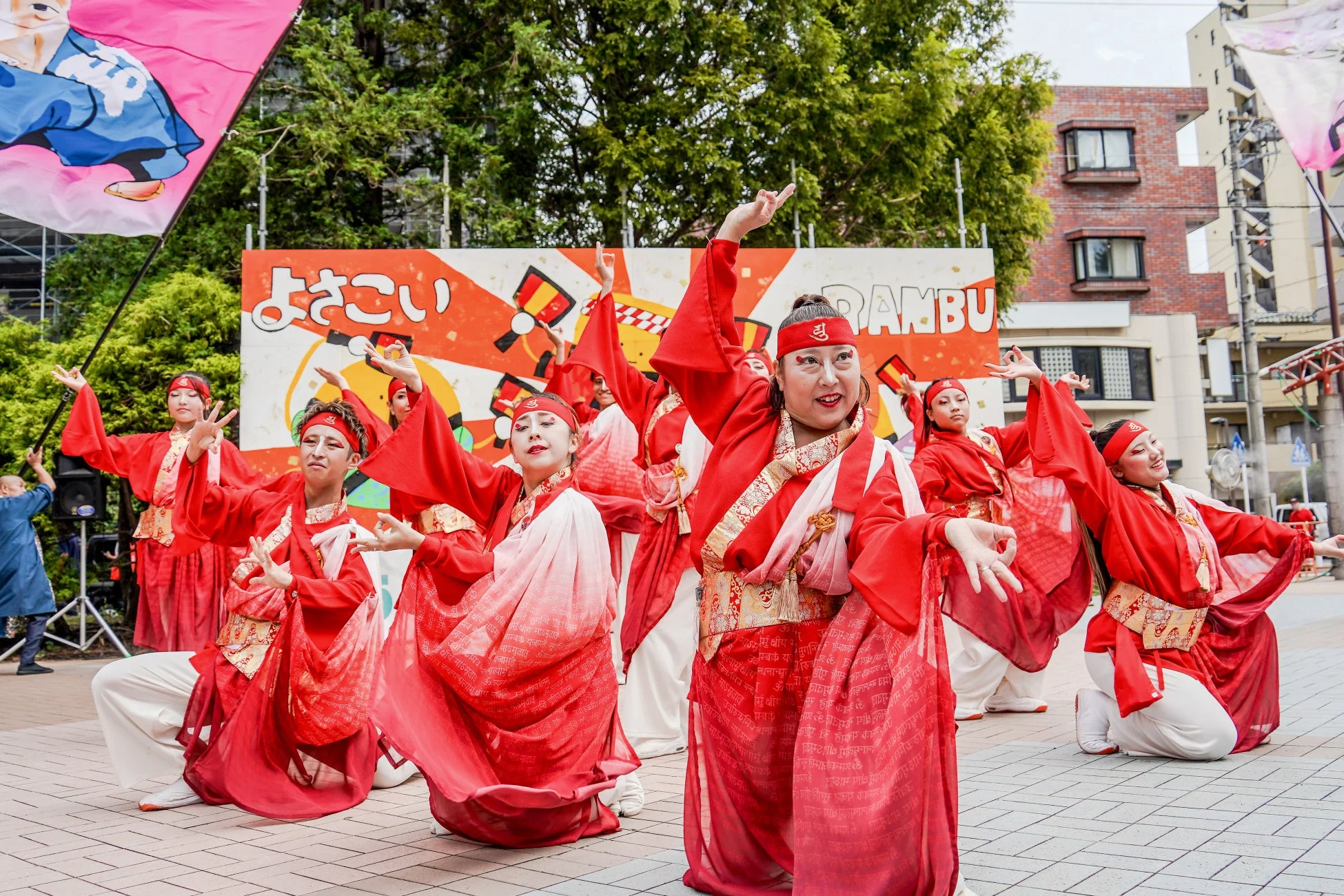 赤い衣装を身につけた人々が、屋外でよさこい祭りの伝統的なダンスを披露している様子