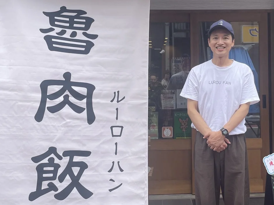 笑顔の男性と魯肉飯の看板