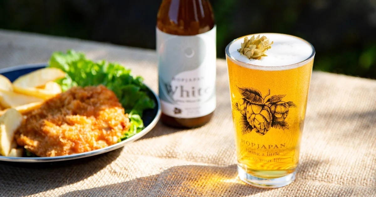 屋外のテーブルに置かれたクラフトビールとフライドチキンやポテト