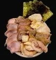 様々な種類のスライスされた肉(チャーシューなど)が皿に盛り付けられ、その奥には海苔が添えられています。ラーメンの具材として提供されるような肉の盛り合わせです。