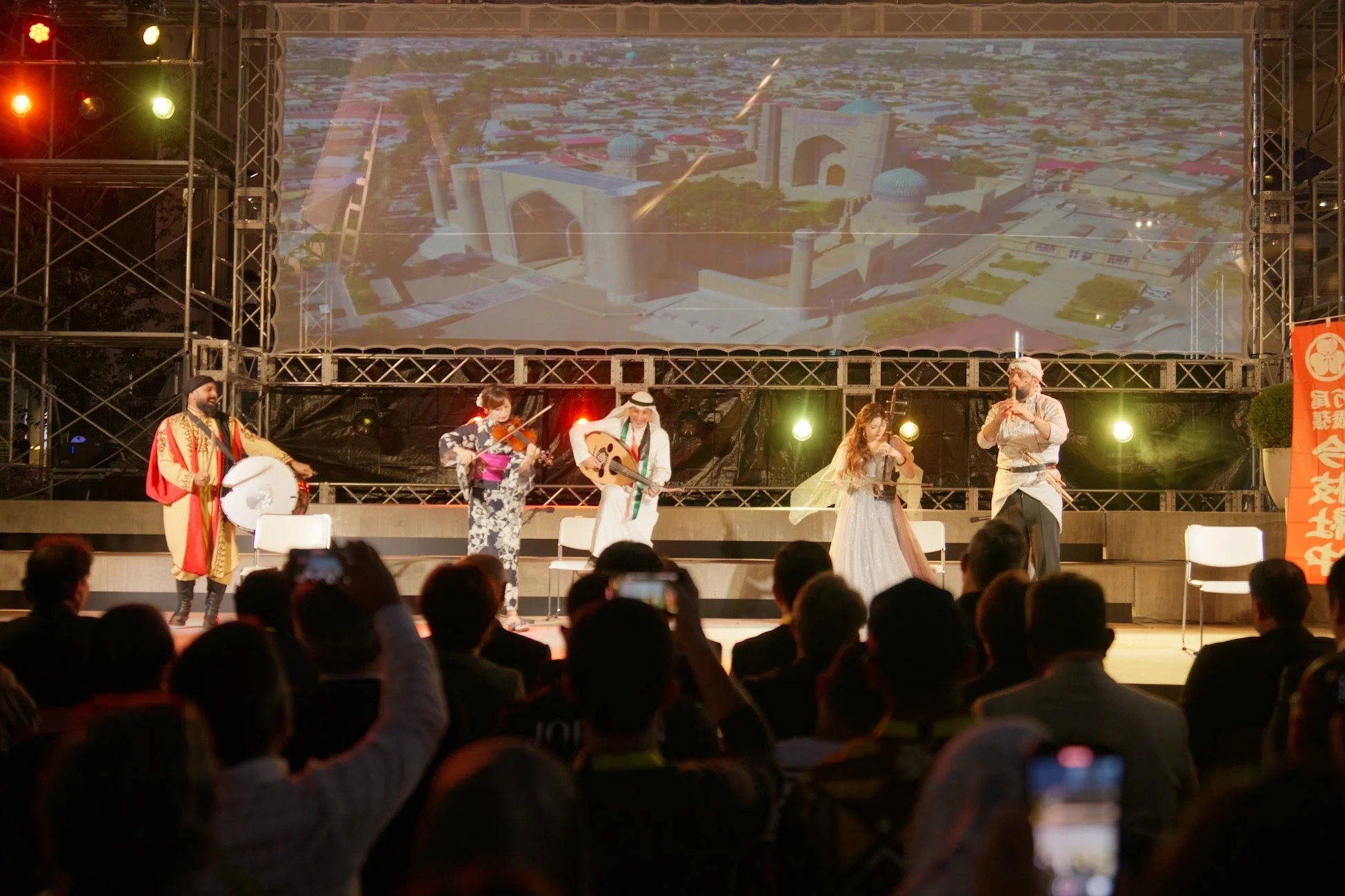 夜のステージで多国籍なミュージシャンが伝統楽器を演奏する文化交流イベント