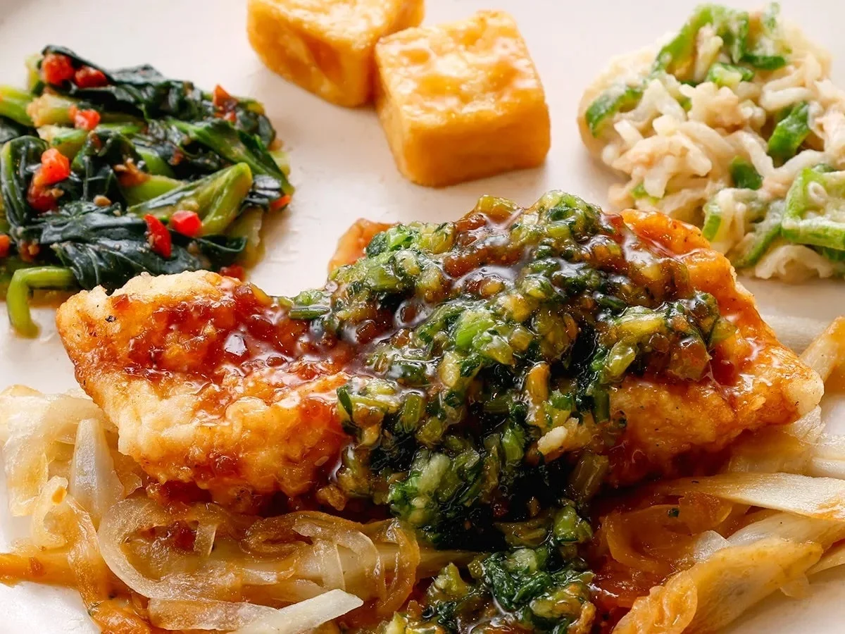 魚のフライをメインに、緑のソースと玉ねぎが添えられた定食