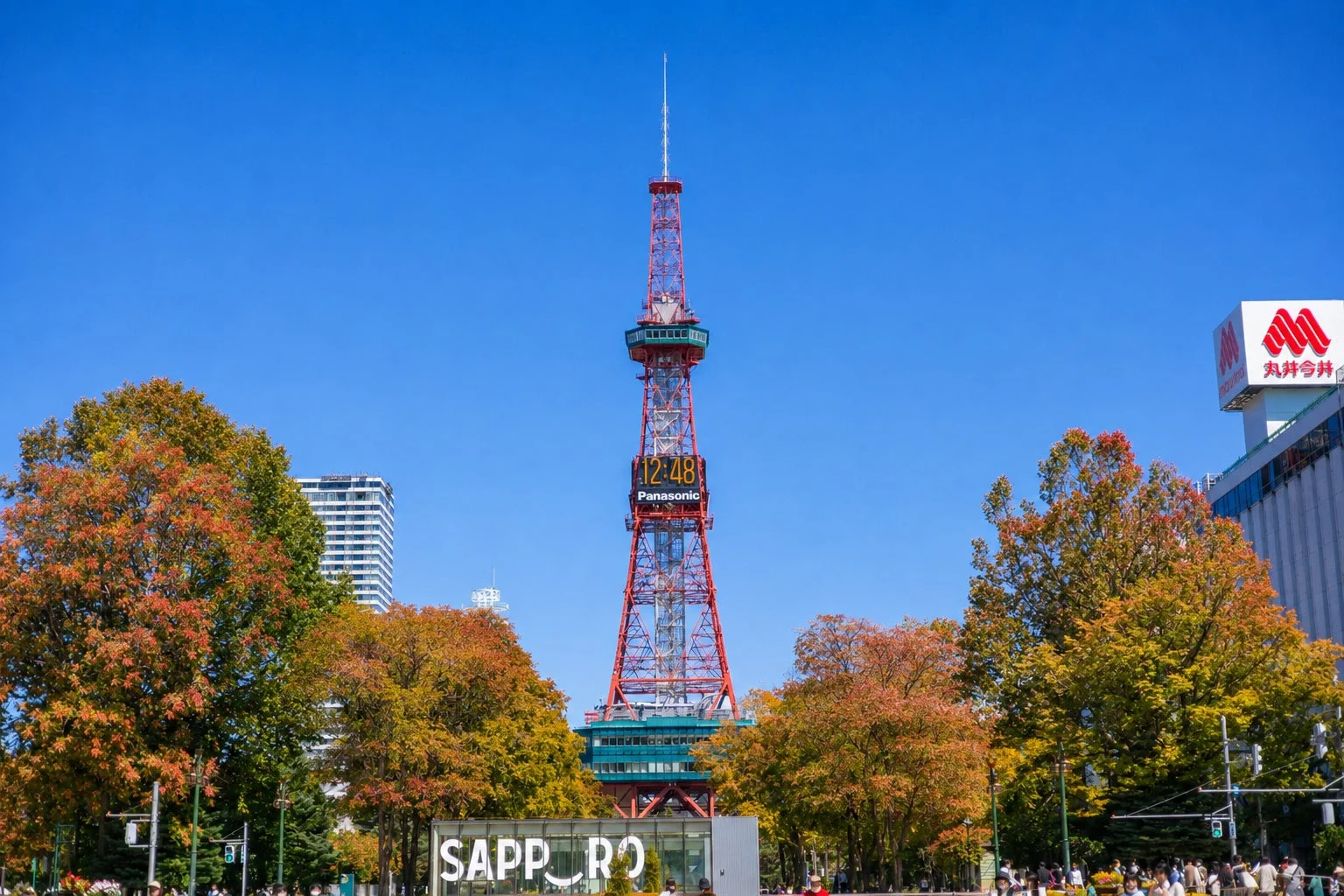 快晴の空の下、秋の紅葉に彩られた札幌テレビ塔が中央にそびえ立つ風景