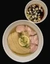 白い器に盛られた、薄切りのチャーシューとレモンスライスが特徴的なあっさり系の麺料理。透明なスープに浸っており、別添えで刻みネギ入りのつけ汁も提供されています。