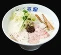 白いクリーミーなスープのラーメンが写っています。チャーシュー、ネギ、メンマ、そして中央には黒いトッピングがのっており、食欲をそそる一杯です。