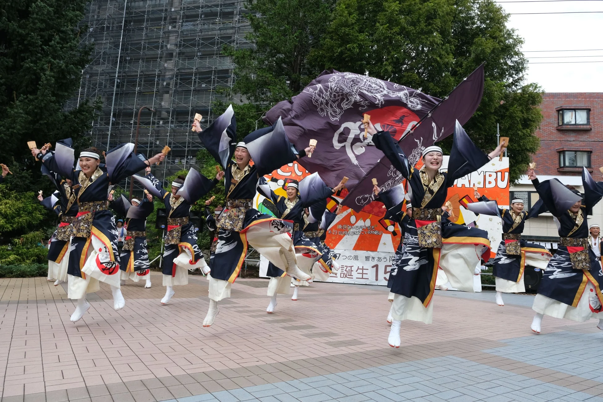 伝統的な衣装を身につけた人々が、屋外のイベントでエネルギッシュによさこいダンスを披露