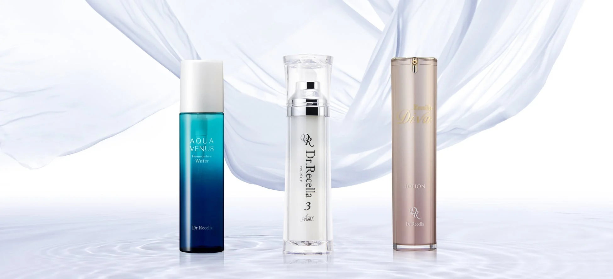 Dr.Recellaのスキンケア製品3本が、水面と白い布を背景に並べられています。青いボトルは化粧水、透明なポンプボトルは美容液、金色のボトルはローションで、清潔感と高級感のあるイメージです。